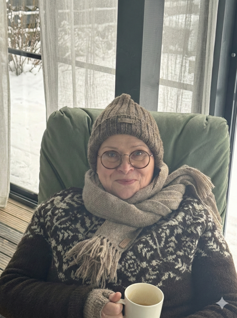 Hanna pipo päässä, huivi kaulassa ja villapaita päällä terassikahvilla.