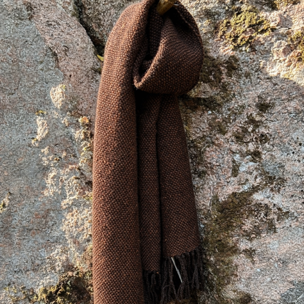 Kaksivärinen ruskea saali roikkumassa kuten kaulassa. Taustalla kallio.