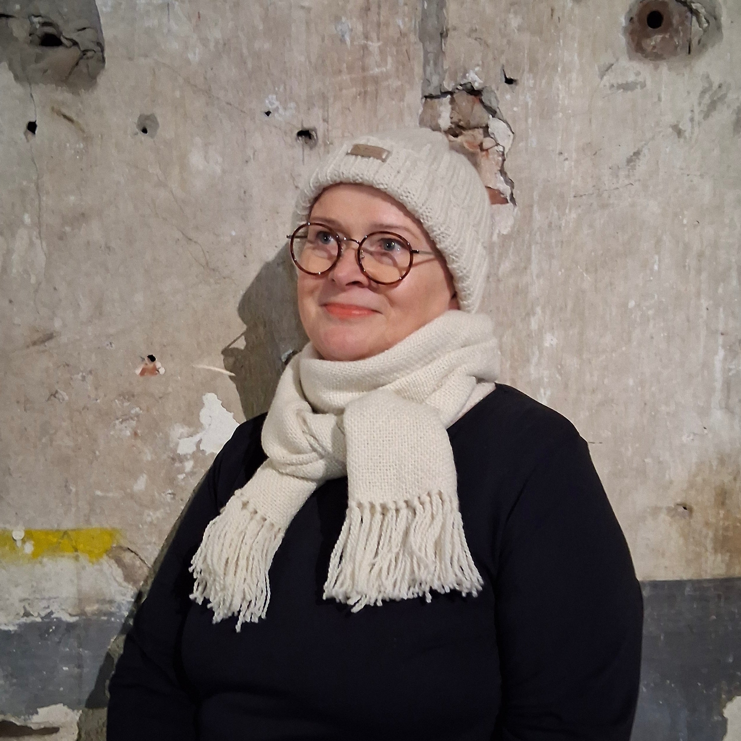 Käsinkudottu luonnonvalkoinen villahuivi naisen kaulassa