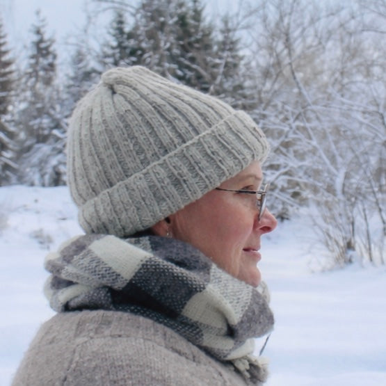 Luonnonvalkoinen pipo Hannan päässä sivulta kuvattuna. Taustalla talvinen maisema.