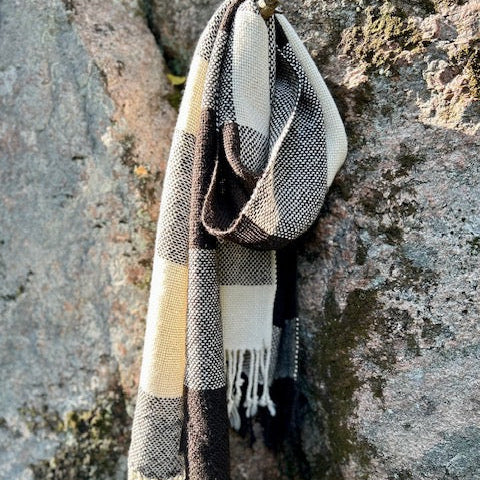 Ruskeavalkoinen ruudulinen villashaali roikkumassa kalliota vasten kuten kaulassa.