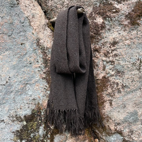 Tummanruskea villashaali roikkumassa kuten kaulassa kalliota vasten.