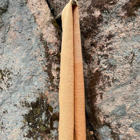 Vaalea oransii villahuivi roikkuu suorana kalliota vasten.